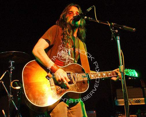 Photo of Shooter Jennings playing acoustic guitar in concert by Marty Temme