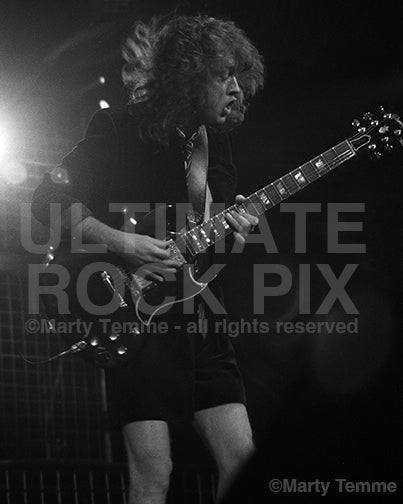 Photo of Angus Young of AC/DC playing a Gibson SG in concert in 1990 by Marty Temme