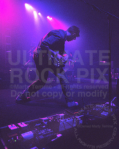 Photo of Ed O'Brien of Radiohead using an EBow while playing a Stratocaster in 1997 by Marty Temme