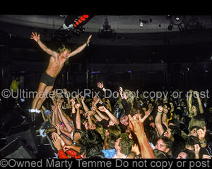 Photo of Axl Rose of Guns N' Roses stagediving into the crowd in 1990 by Marty Temme