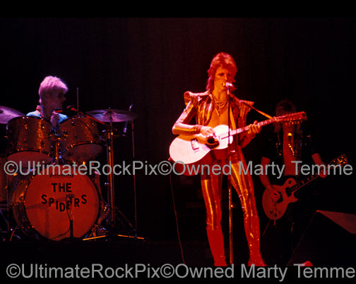 Photo of David Bowie, Mick Ronson and Woody Woodmansey in concert in 1973 by Marty Temme