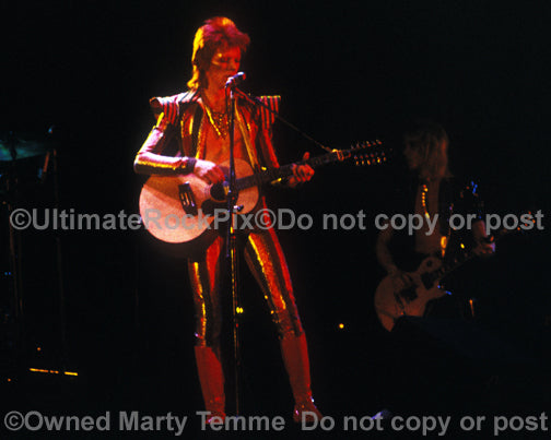 Photo of David Bowie playing acoustic guitar onstage in 1973 by Marty Temme