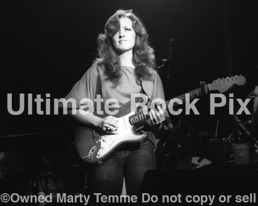 Black and white photo of guitarist Bonnie Raitt playing slide on a Fender Stratocaster in concert in 1980 by Marty Temme