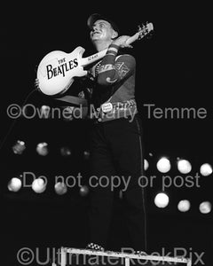 Photo of Rick Nielsen of Cheap Trick holding guitar with words "The Beatles" on it by Marty Temme