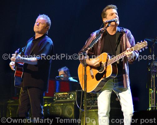 Photos of Glenn Frey and Don Henley of The Eagles playing acoustic guitar in concert by Marty Temme