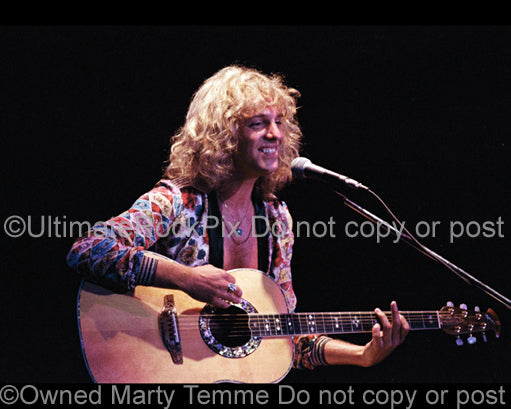 Photo of Peter Frampton playing acoustic guitar in concert in 1974 by Marty Temme