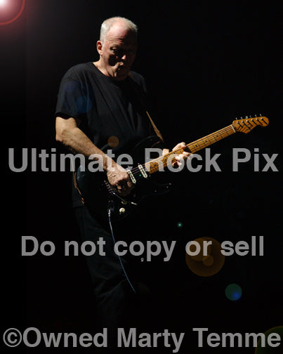 Photo of David Gilmour of Pink Floyd playing his black Stratocaster in concert by Marty Temme