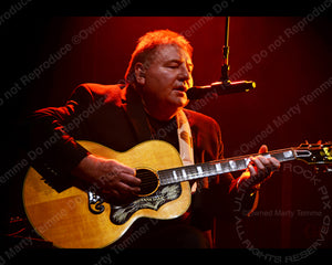 Photo of Greg Lake of ELP playing acoustic guitar in concert in 2012 by Marty Temme