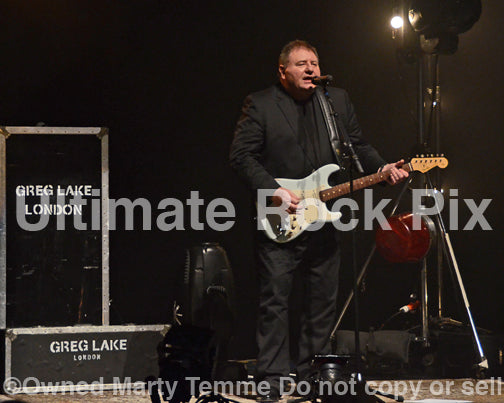 Photo of Greg Lake singing and playing a Fender Stratocaster in concert in 2012 by Marty Temme