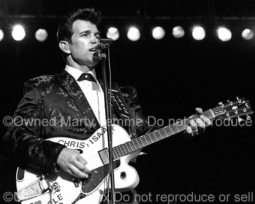 Photo of Chris Isaak playing a hollow body Gibson guitar in concert by Marty Temme