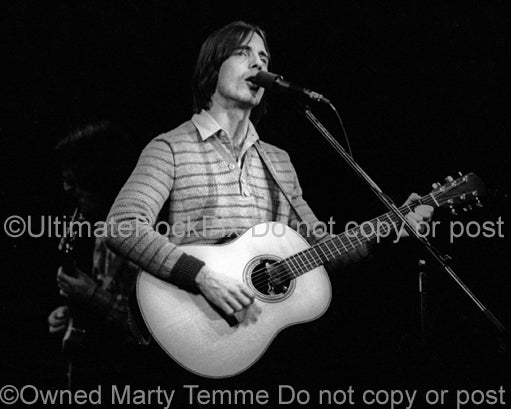 Photo of musician Jackson Browne playing acoustic guitar in concert in 1978 by Marty Temme