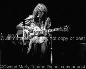 Black and white photo of Joni Mitchell playing guitar in concert in 1979 by Marty Temme