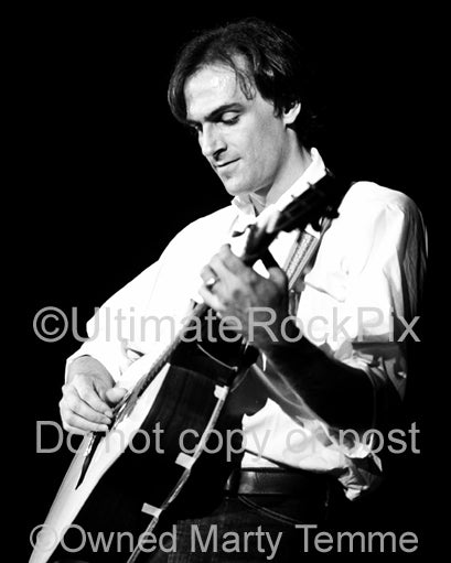 Black and white photo of James Taylor playing guitar in concert in the 1970's by Marty Temme
