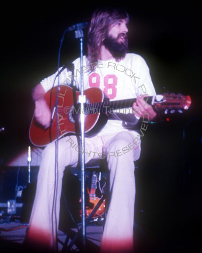 Photo of Kenny Loggins of Loggins and Messina playing an acoustic guitar in concert in 1973 by Marty Temme
