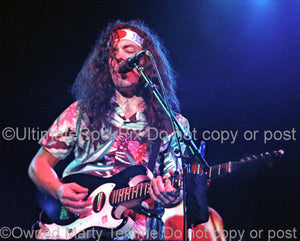 Photo of musician David Lindley playing a Sears Silvertone guitar in concert by Marty Temme
