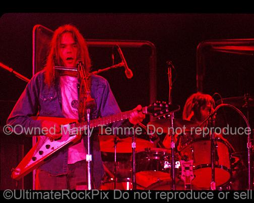 Photo of Neil Young and John Barbata performing in concert in 1973 by Marty Temme