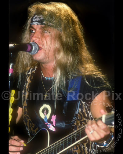 Photo of Bret Michaels of Poison playing guitar in concert in 1990 by Marty Temme