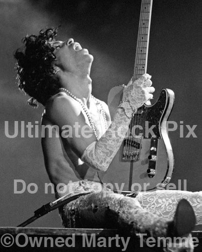 Black and white photo of Prince playing guitar in concert in 1984 by Marty Temme