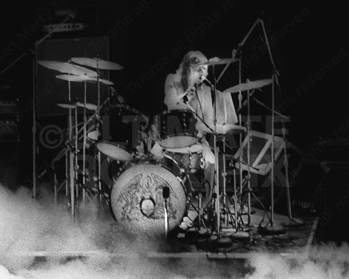 Photo of Roger Taylor of Queen playing drums in concert in 1975 by Marty Temme