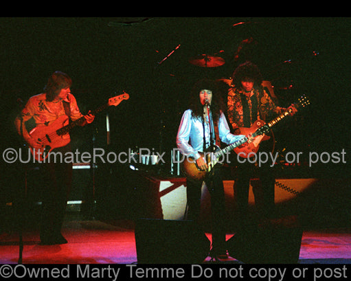 Photo of Kevin Cronin, Bruce Hall and Gary Richrath of REO Speedwagon in concert in 1977 by Marty Temme
