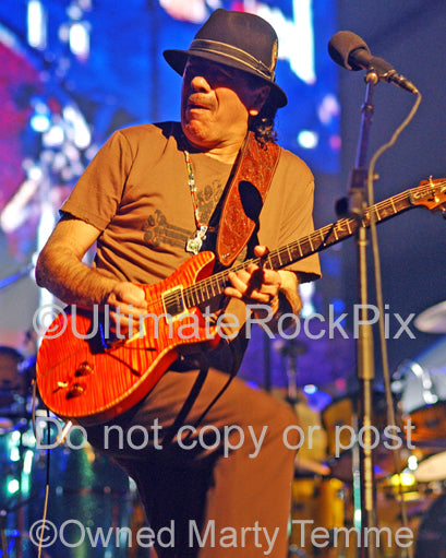 Photo of musician Carlos Santana of Santana playing a PRS guitar in concert by Marty Temme