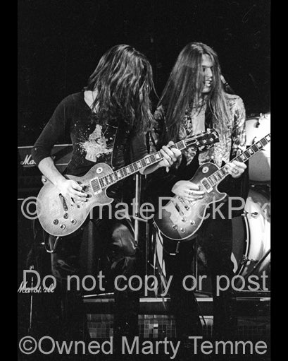 Photo of Gary Moore and Scott Gorham of Thin Lizzy in concert in 1977 by Marty Temme