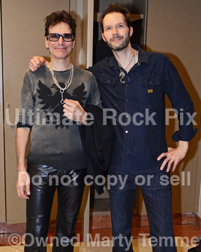 Photo of Steve Vai and Paul Gilbert standing together backstage after a concert in 2012 in Anaheim, California by Marty Temme