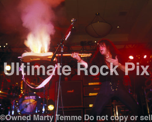Photo of Yngwie Malmsteen with his guitar on fire in concert in 1994 by Marty Temme
